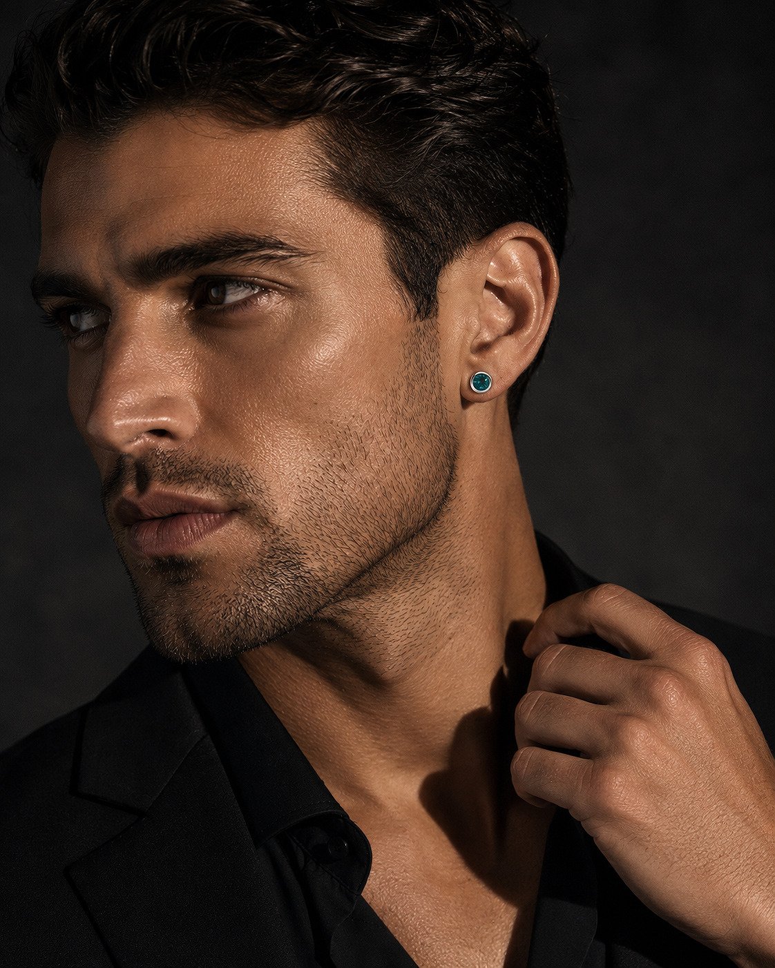 Editorial portrait of a man wearing a color-changing alexandrite stud earring in 14K white gold.