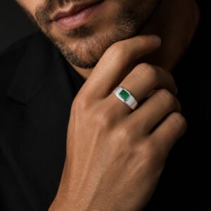 Adult male model wearing The Verdant Crown 14K white gold emerald men's ring in a dark luxury studio.